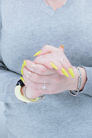 Female hand with long nails and a bottle of bright yellow green neon nail polishの写真素材