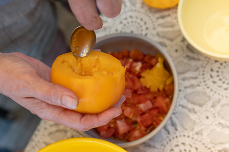 Red Peppers, yellow tomatoes, white zucchini and grape leaves stuffed with minced meat. People hands are preparing food.の写真素材
