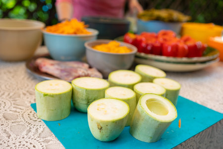 Red Peppers, yellow tomatoes, white zucchini and grape leaves stuffed with minced meat. People hands are preparing food.の写真素材
