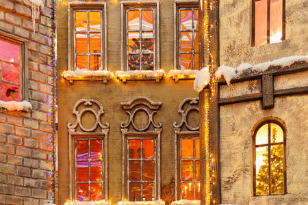 Background for design. New Year's decorations, toys and garlands on the windows in fabulous scenery. Houses for children in a public place.の写真素材