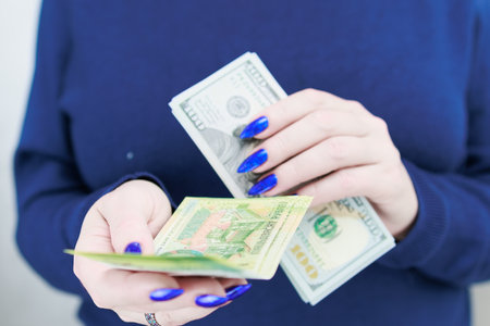 Female hands holding paper bills of US dollars and Belarusian rublesの写真素材