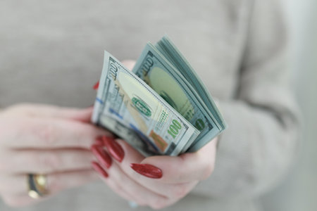 woman's hands holding American dollar paper bills