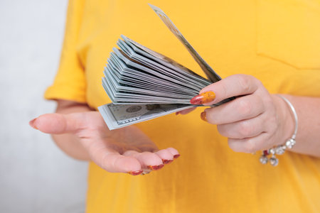 woman's hands holding American dollar paper bills