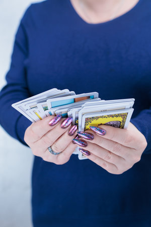 Female hands holding tarot cards for fortune telling and tricks