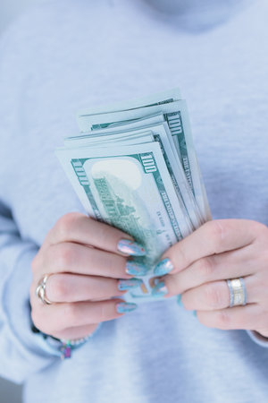 female hands holding American dollar paper billsの写真素材