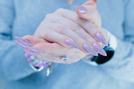 Woman hand with long nails manicure and light blue and pink nail polishの写真素材