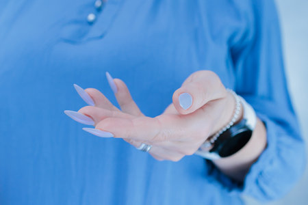 Woman's beautiful hand with long nails and light baby blue manicure