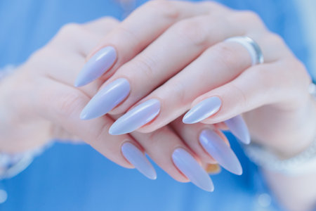 Woman's beautiful hand with long nails and light baby blue manicure
