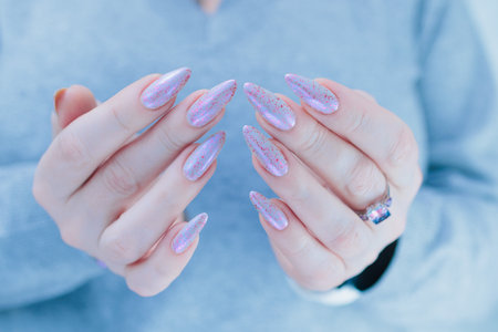 Woman hand with long nails manicure and light blue and pink nail polishの写真素材