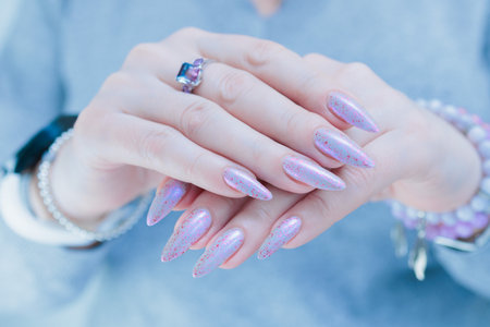 Woman hand with long nails manicure and light blue and pink nail polishの写真素材