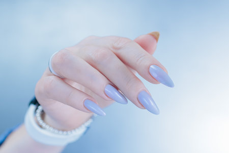 Woman's beautiful hand with long nails and light baby blue manicureの写真素材