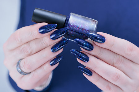 Woman's beautiful hand with long nails and dark blue manicure