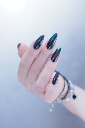 Woman's beautiful hand with long nails and dark blue and black manicureの写真素材