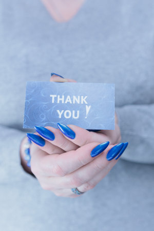 Female hands hold a picture with the inscription Thank youの写真素材