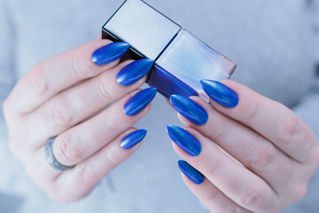 Woman's beautiful hand with long nails and bright blue manicure