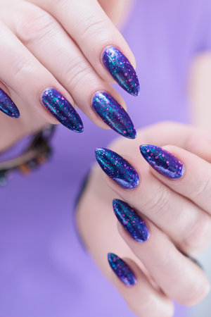 Female hand with long nails and a blue and lilac color nail polishの写真素材