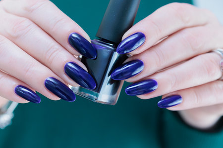 Female hand with long nails and purple blue manicure