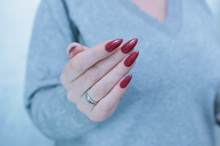 Female hands with long nails and dark red nail polishの写真素材