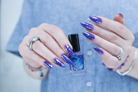 Female hand with long nails and a blue and purple color nail polish