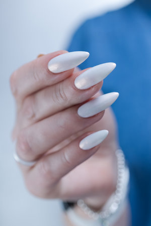 Woman's hands with long nails and a light white color nail polishの写真素材