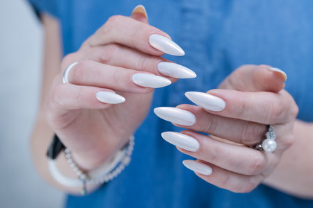 Woman's hands with long nails and a light white color nail polishの写真素材