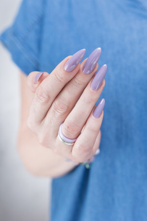 Female hand with long nails and a lilac nude nail polishの写真素材