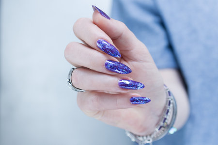 Female hand with long nails and a blue and purple color nail polishの写真素材