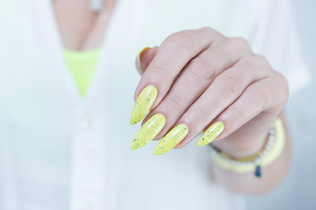 Female hand with long nails and neon yellow green manicureの写真素材