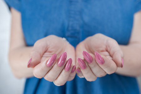 Female hands with long nails and a light pink color nail polishの写真素材