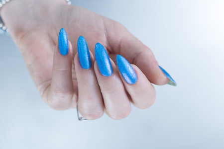 Woman's beautiful hand with long nails and bright blue manicureの写真素材