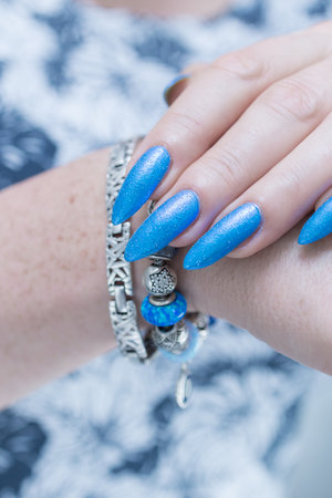 Female hand with long nails and bright light blue and silver manicureの写真素材