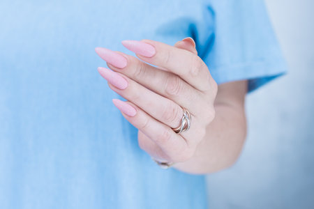Woman's hands with long nails and a light pink color nail polishの写真素材
