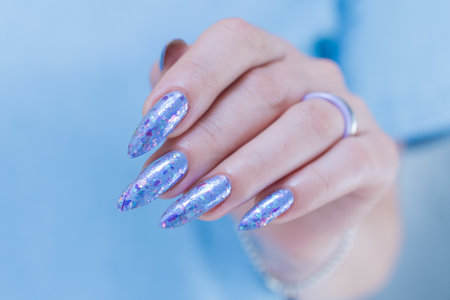 Female hand with long nails and bright light blue and silver manicureの写真素材