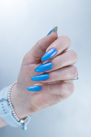 Woman's beautiful hand with long nails and baby blue manicureの写真素材
