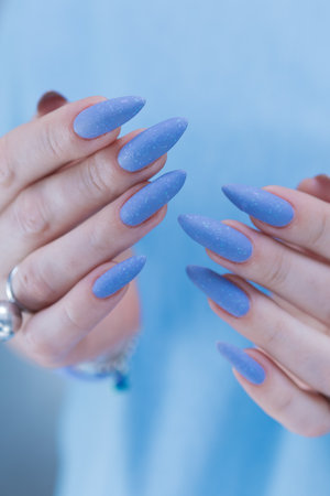 Woman's beautiful hand with long nails and bright blue manicureの写真素材