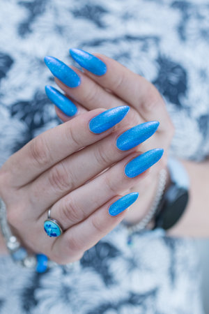 Woman's beautiful hand with long nails and bright blue manicureの写真素材