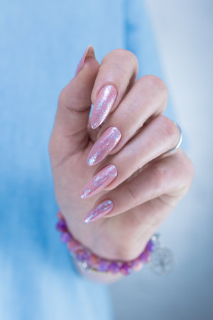 Female hands with long nails and a light pink color nail polishの写真素材