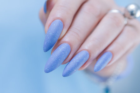 Woman's beautiful hand with long nails and bright blue manicureの写真素材