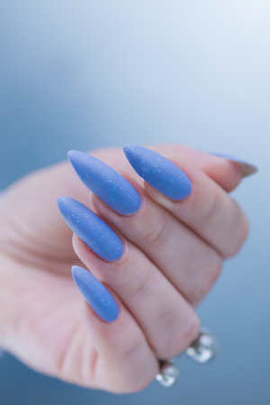 Woman's beautiful hand with long nails and bright blue manicureの写真素材