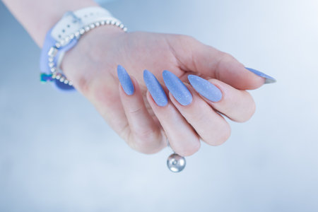Woman's beautiful hand with long nails and baby blue manicureの写真素材