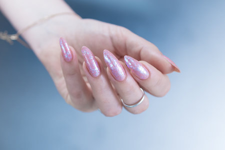 Woman's hands with long nails and a light pink color nail polish