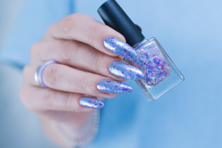 Female hand with long nails and bright light blue and silver manicureの写真素材