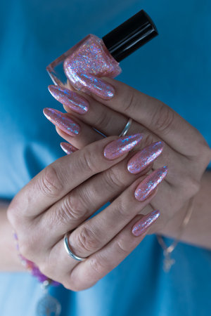 Female hands with long nails and a light pink color nail polishの写真素材