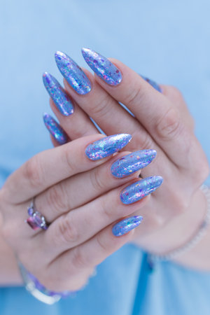 Female hand with long nails and bright light blue and silver manicureの写真素材