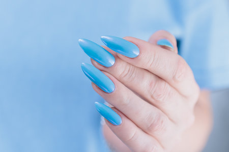 Woman's beautiful hand with long nails and baby blue manicureの写真素材