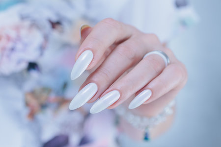 beautiful female hands with long nails light white manicureの写真素材