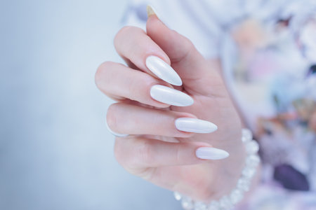 beautiful female hands with long nails light white manicureの写真素材