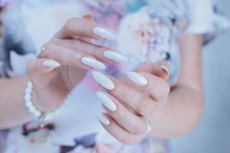 beautiful female hands with long nails light white manicureの写真素材