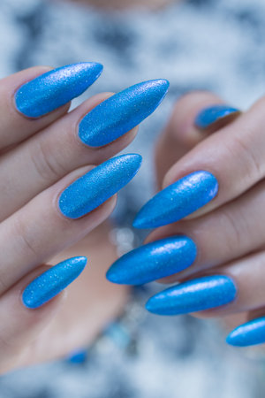 Woman's beautiful hand with long nails and bright blue manicureの写真素材