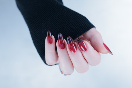 Woman hand with long nails and a red and black nail polishの写真素材